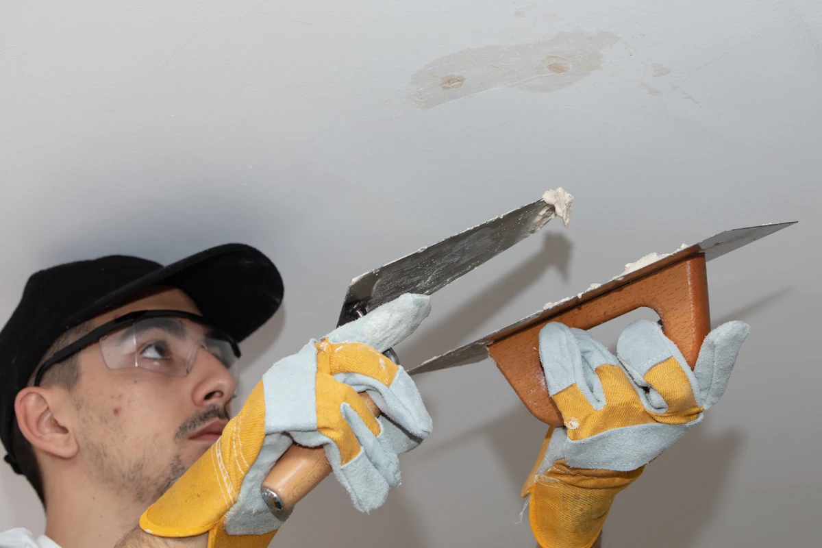 Un homme qui applique de l'enduit sur un plafond