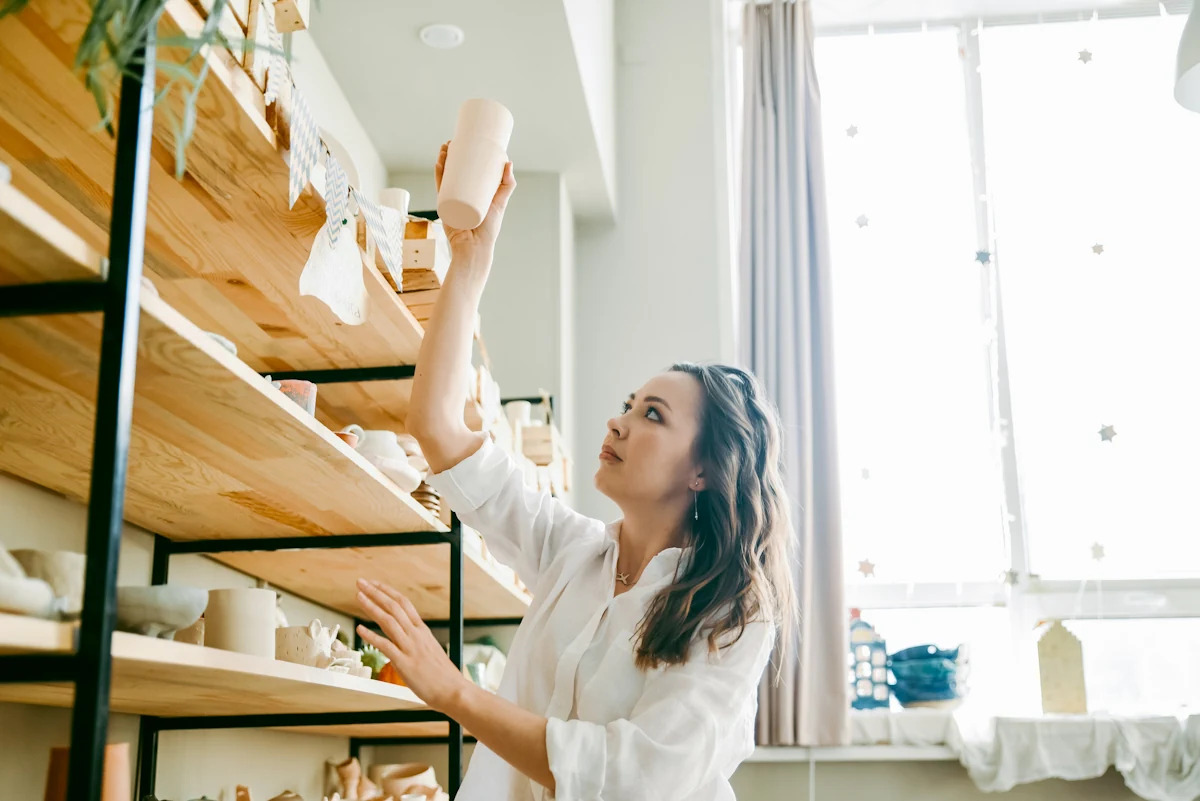 Une femme qui range un étagère sur un mur en placo