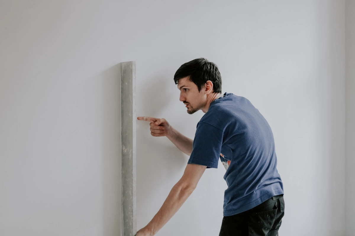 un homme qui vérifie un mur en placo