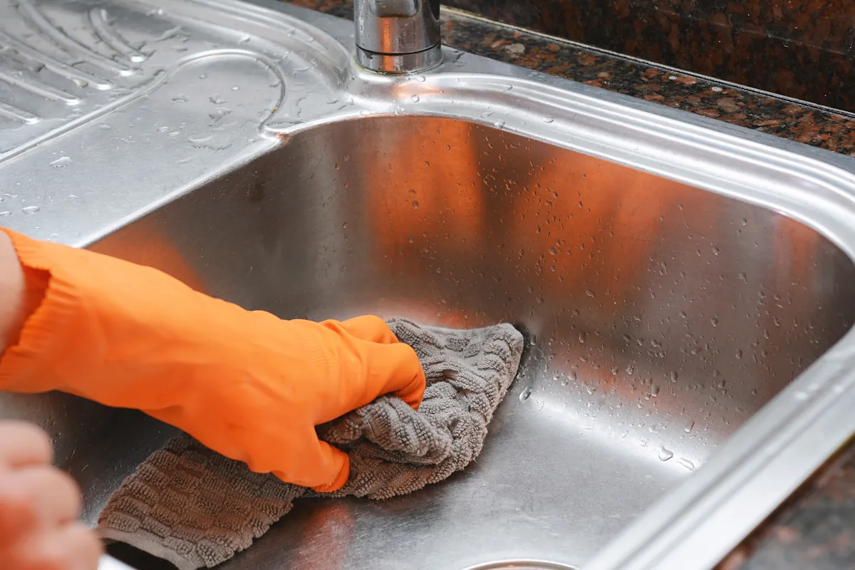 Une personne qui nettoie un évier inox