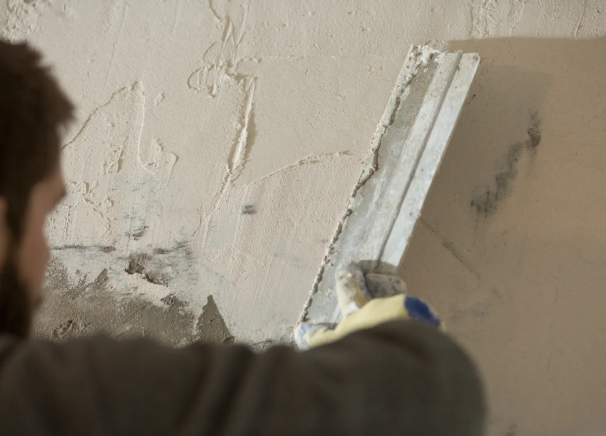 Un homme qui applique de l'enduit hydraulique traditionnel sur un mur