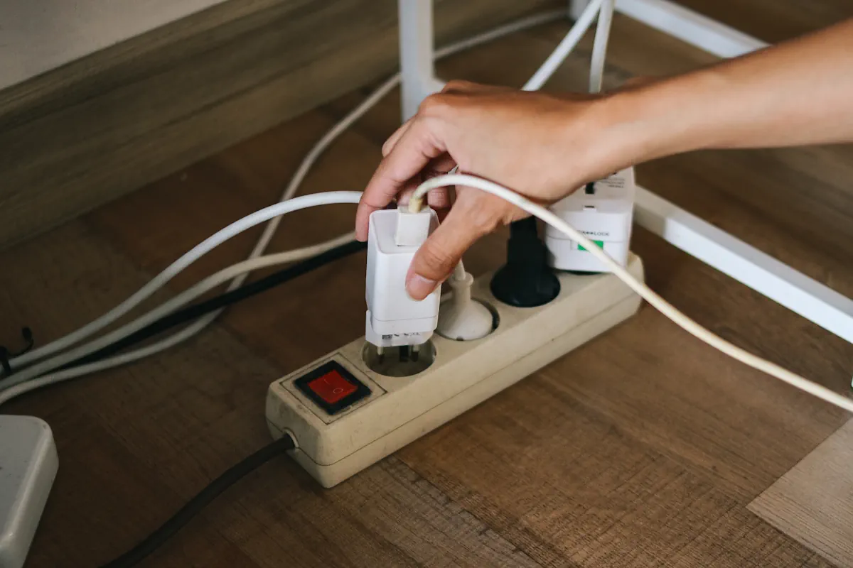 Une personne qui branche un chargeur sur une multiprise fixée