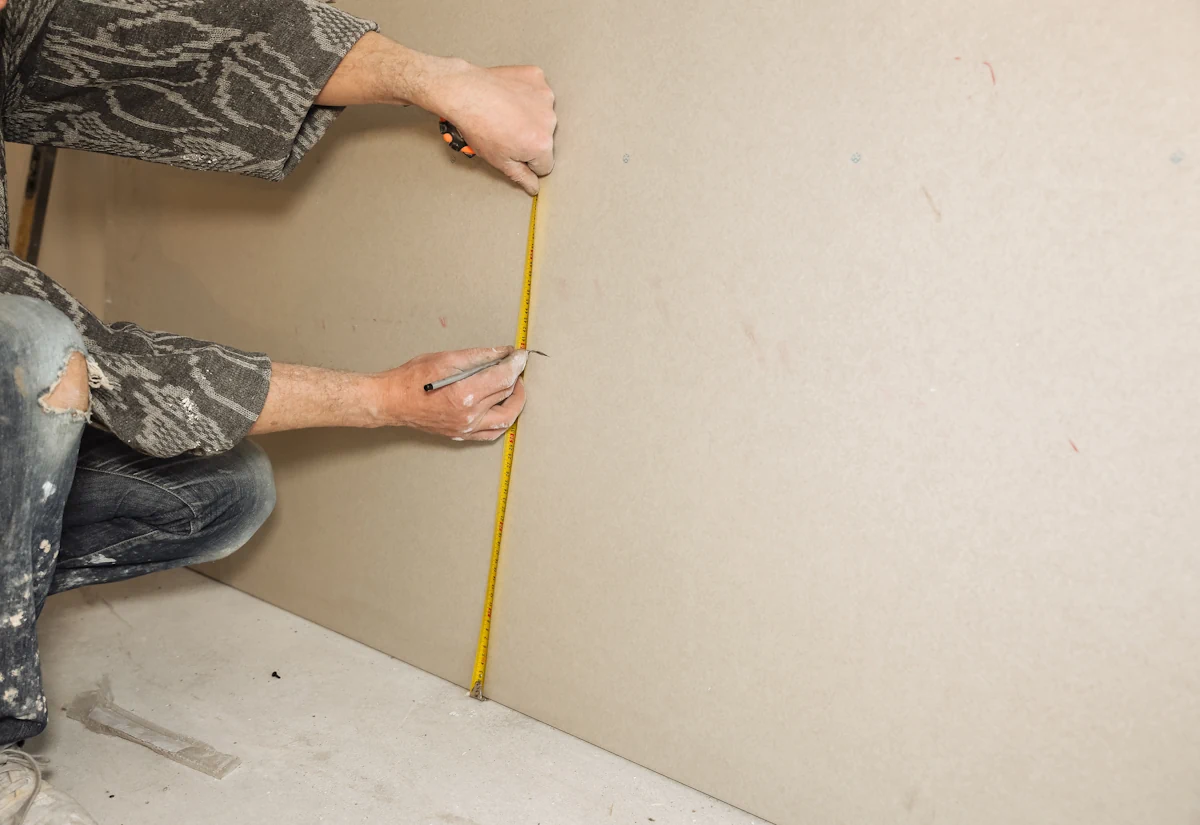 une personne qui prend des mesures sur un mur en placo